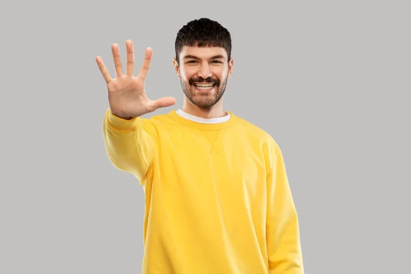 Smiling young man showing his hand or five fingers — Stok fotoğraf
