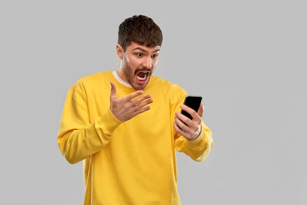 Angry young man with smartphone — Stockfoto