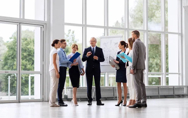 Team di lavoro con schema su lavagna a fogli mobili in ufficio — Foto Stock