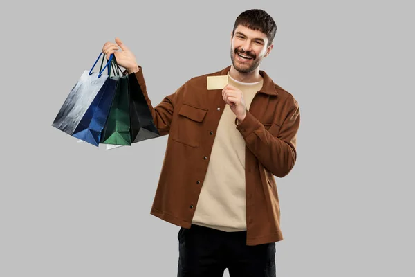 Boldog fiatalember bevásárló táskákkal és hitelkártyával — Stock Fotó