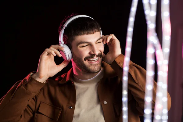 Man in headphones over neon lights of night club — Stock Photo, Image