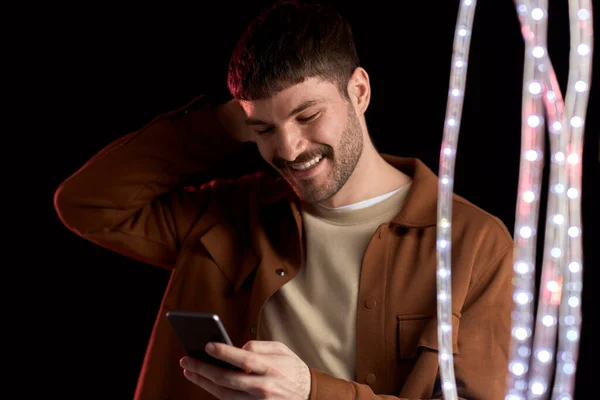 Счастливый улыбающийся молодой человек со смартфоном — стоковое фото