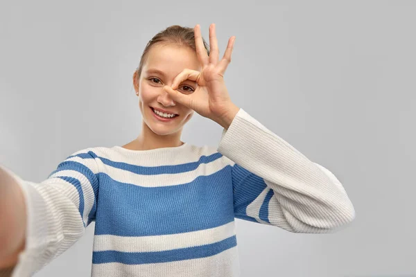 Usmívající se dospívající dívka ve svetru přičemž selfie — Stock fotografie
