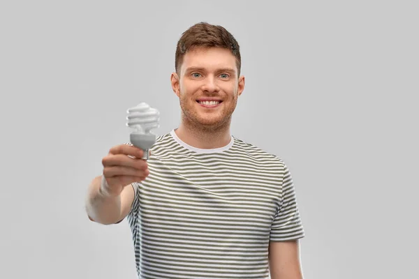 Усміхнений молодий чоловік тримає лампочку освітлення — стокове фото