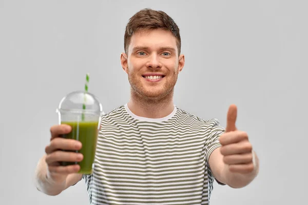Happy man with green smoothie showing thumbs up — Stockfoto