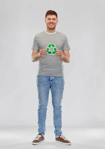 Улыбающийся молодой человек держит зеленый знак утилизации — стоковое фото