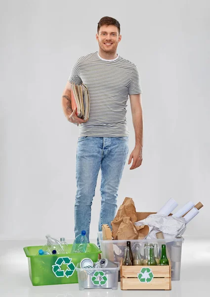 Улыбающийся человек сортирует бумагу, металл и пластиковые отходы — стоковое фото