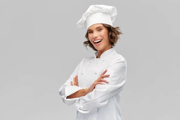 Glimlachende vrouwelijke chef in toque met gekruiste armen — Stockfoto