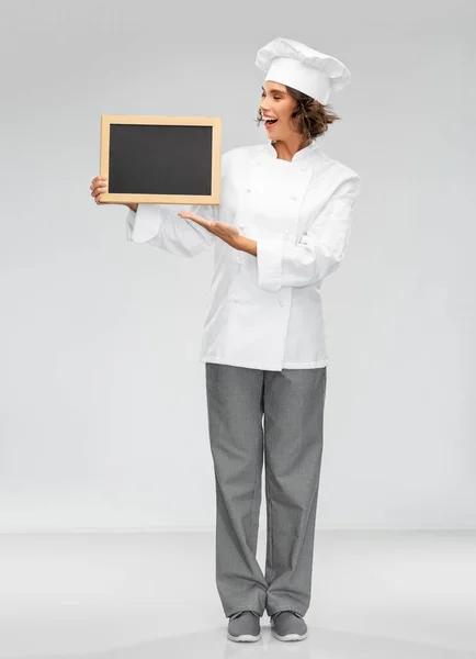 Sorridente chef feminino segurando quadro preto — Fotografia de Stock