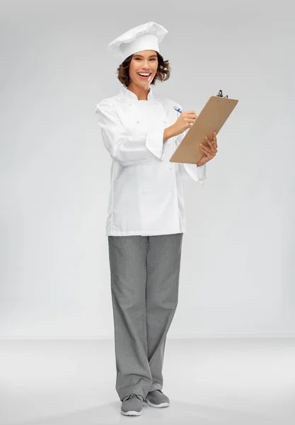 Chef feminino sorridente no toque com prancheta — Fotografia de Stock