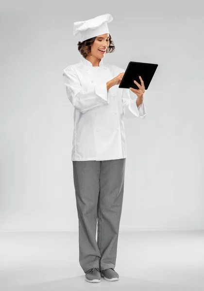 Lachende vrouwelijke chef-kok in toque met tablet computer — Stockfoto