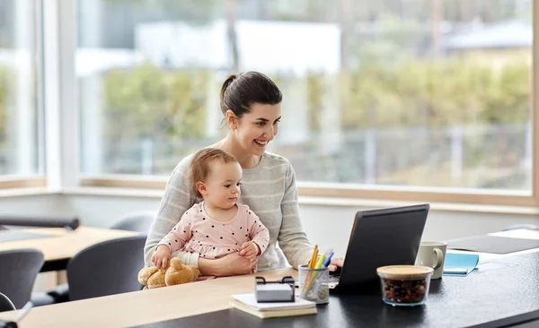 Madre con el bebé y el ordenador portátil trabajando en la oficina en casa — Foto de Stock