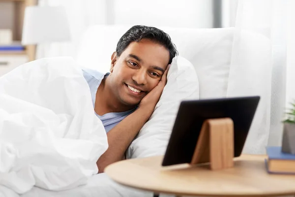 Hombre indio feliz con la tableta PC en la cama en casa —  Fotos de Stock