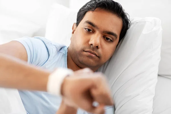 Indio hombre mirando inteligente reloj en la cama en casa —  Fotos de Stock