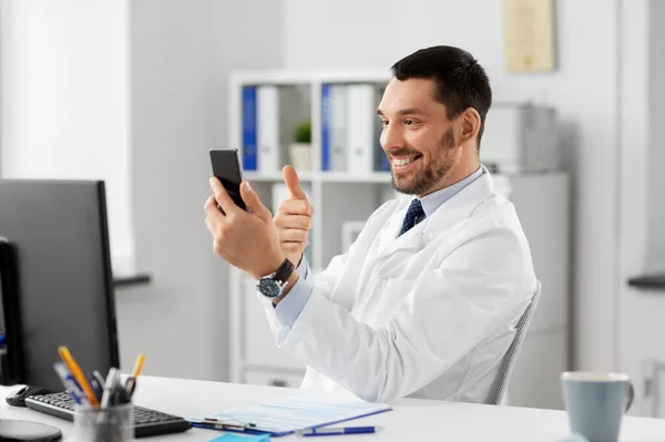 Läkare med smartphone som har videosamtal på kliniken — Stockfoto