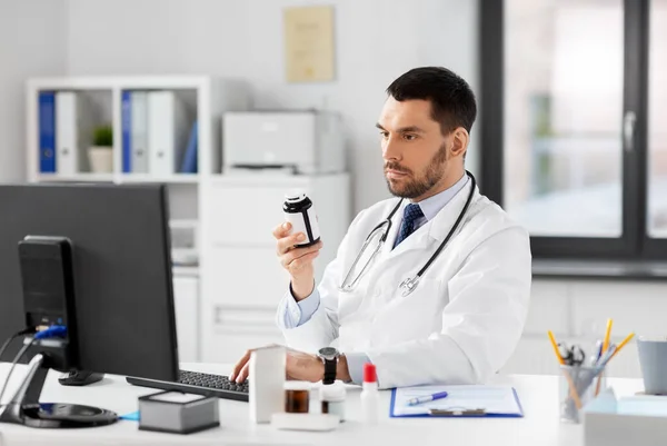 Male doctor with medicine and computer at hospital — Stock Photo, Image