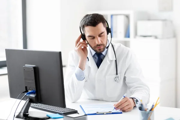 Doctor masculino con auriculares y portapapeles en el hospital —  Fotos de Stock