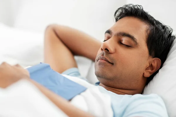 Homme indien avec livre dormir dans le lit à la maison Photos De Stock Libres De Droits