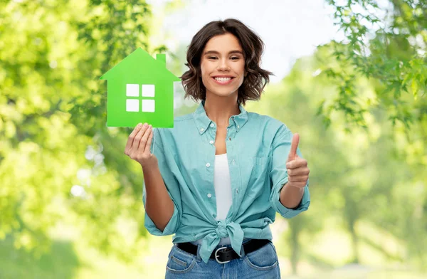 Glimlachende vrouw met groene huis tonen duimen omhoog — Stockfoto