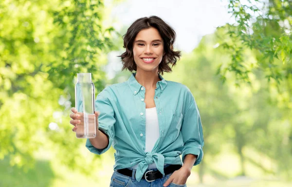 Sonriente joven mujer sosteniendo agua en botella de vidrio — Foto de Stock
