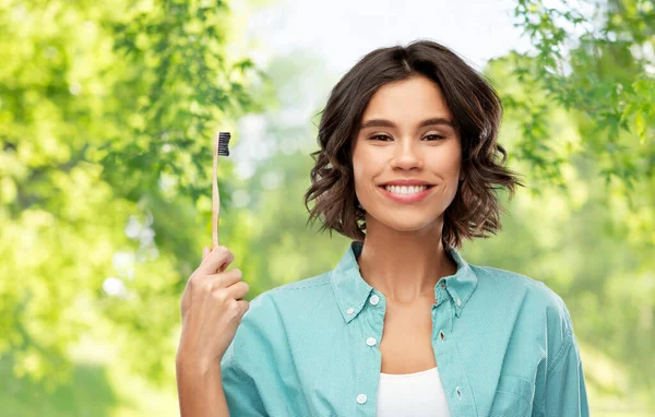 Giovane donna sorridente con spazzolino in legno — Foto Stock