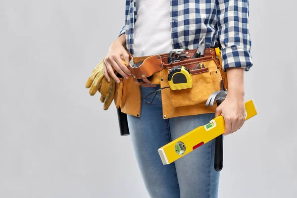 Mulher construtor com nível e ferramentas de trabalho na correia — Fotografia de Stock