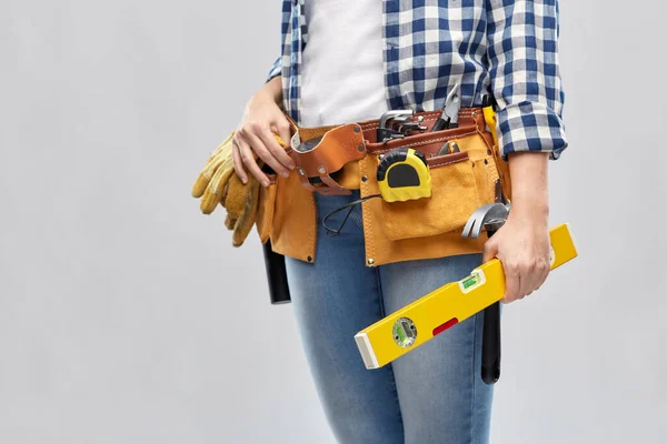 Woman builder with level and working tools on belt — Stock Photo, Image