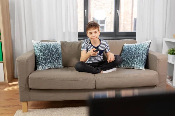 Unatkozó fiú távirányítóval tv-t néz otthon — Stock Fotó