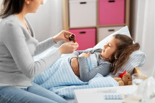 Mãe derramando xarope de tosse para filha doente — Fotografia de Stock