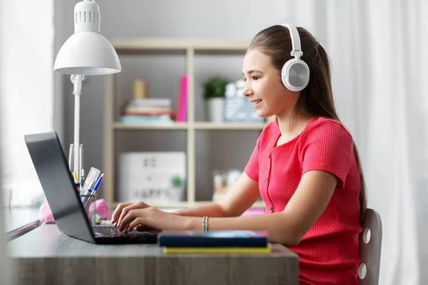Girl in headphones with laptop computer at home — Stock Photo, Image