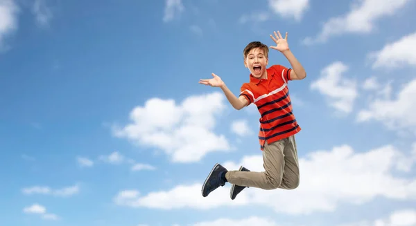 Glad leende ung pojke hoppar i luften över himlen — Stockfoto