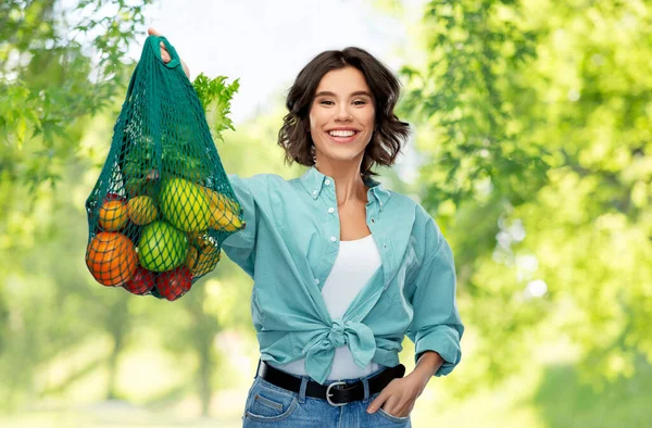 Mujer sonriente feliz con comida en bolsa de red reutilizable —  Fotos de Stock