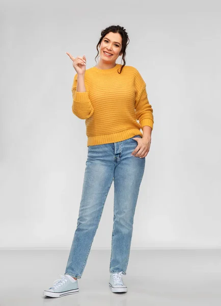 Feliz joven sonriente apuntando con el dedo hacia arriba — Foto de Stock