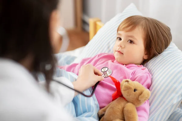 Médico con estetoscopio y niña enferma en la cama —  Fotos de Stock