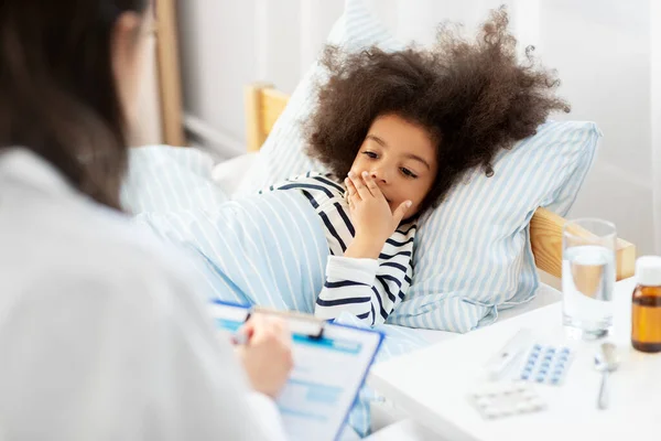 Doctor with clipboard and sick girl in bed at home — Stock Photo, Image