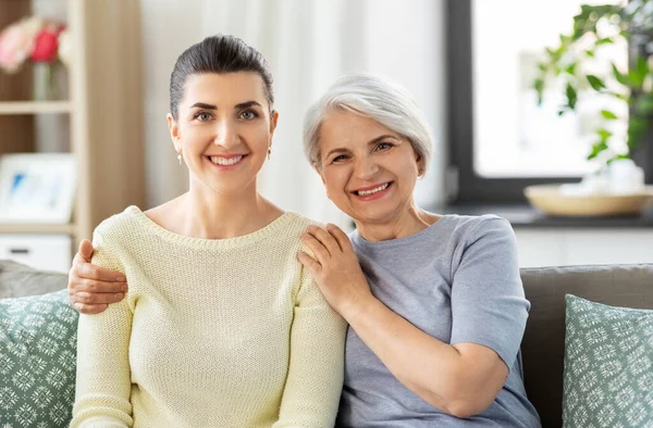 Senior Mutter mit erwachsener Tochter umarmt zu Hause — Stockfoto