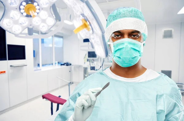 Indian surgeon with scalpel over operating room — Stock Photo, Image