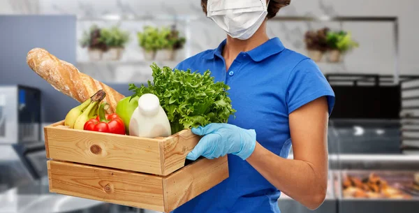 Levering vrouw in gezicht masker met voedsel in doos — Stockfoto