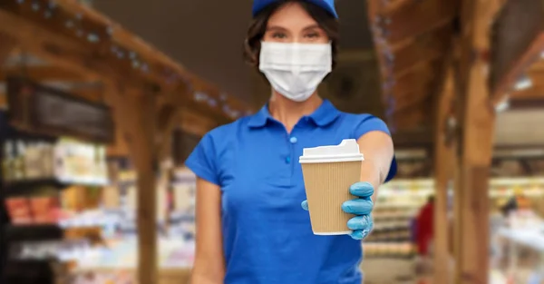 Saleswoman in face mask with takeaway coffee cup — Stock Photo, Image
