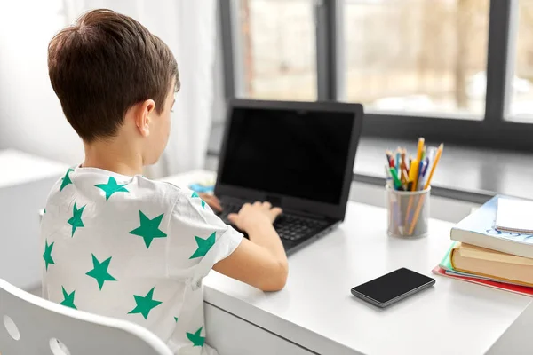 Estudante menino digitando no computador portátil em casa — Fotografia de Stock