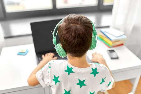 Niño en auriculares con ordenador portátil en casa —  Fotos de Stock