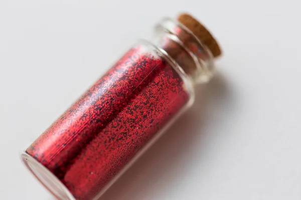 Κόκκινο glitters σε μπουκάλι πάνω από λευκό φόντο — Φωτογραφία Αρχείου