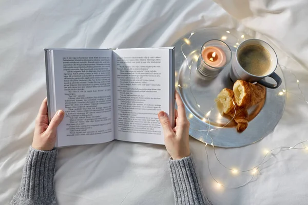 Mãos de mulher com livro, café e croissants — Fotografia de Stock