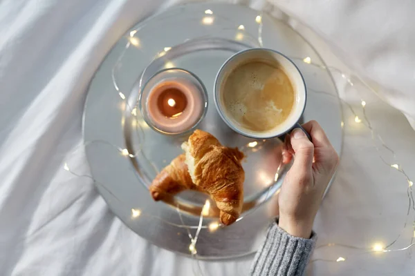 Hand einer Frau, die Kaffee mit Croissant trinkt — Stockfoto