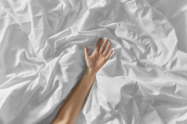 Hand einer Frau, die auf zerknautschtem Bettlaken liegt — Stockfoto