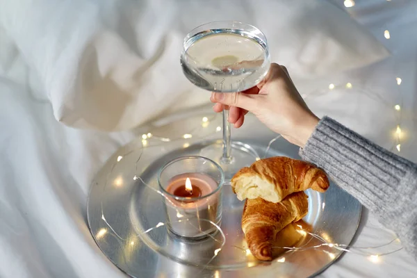 Hand van vrouw met champagne met croissants — Stockfoto