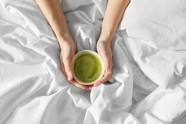 Manos de mujer con taza de té matcha en la cama —  Fotos de Stock