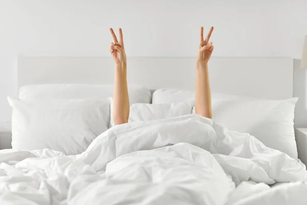 Manos de mujer acostada en la cama y mostrando paz —  Fotos de Stock