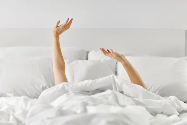 Manos de mujer acostada en la cama y estirándose —  Fotos de Stock