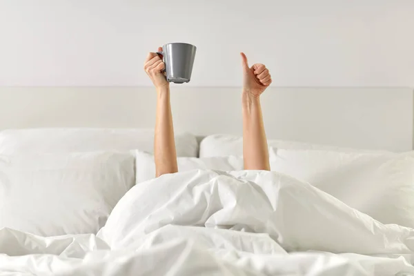 Mujer con café acostado en la cama mostrando los pulgares hacia arriba —  Fotos de Stock